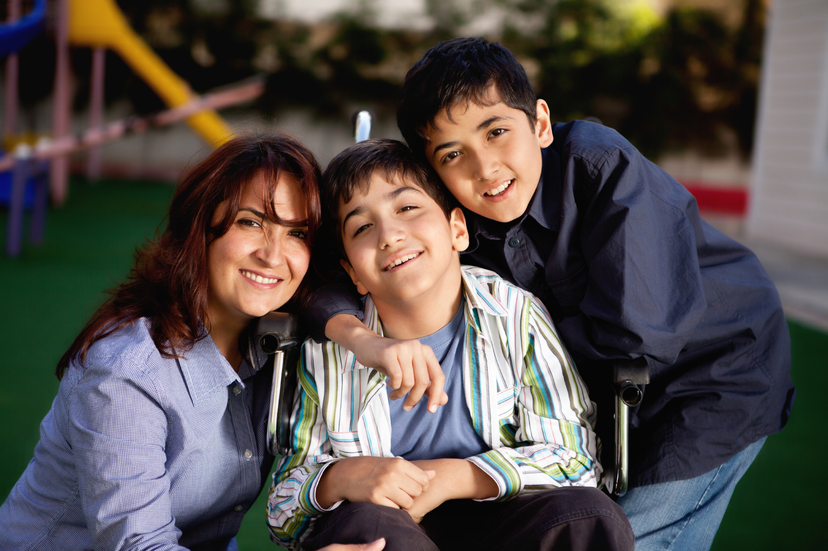 A young boy in a wheelchair with his brother and mother