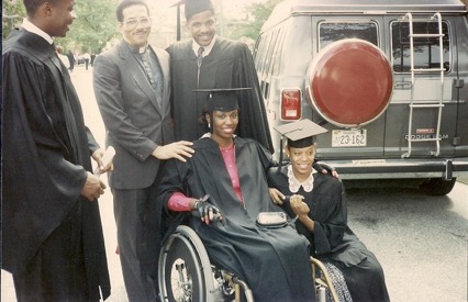 Carmen Jones, in her wheelchair and cap-and-gown, surrounded by 4 people