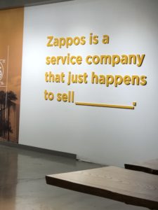 A wall at the Zappos office reads 'Zappos is a service company that just happens to sell _______.'